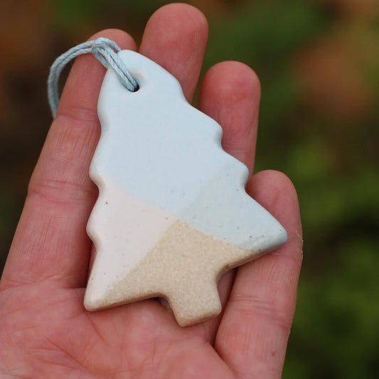 Ceramic Christmas tree ornament held in a hand with a blurred natural background