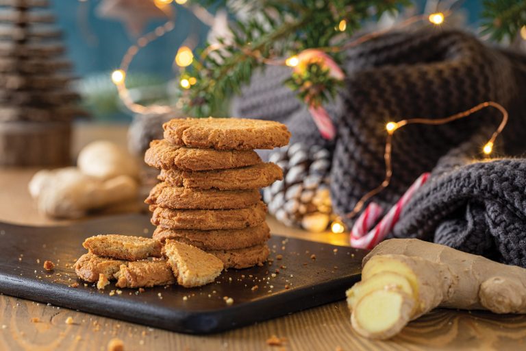 Stack of gingerbread cookies on a wooden board with Christmas decorations in the background