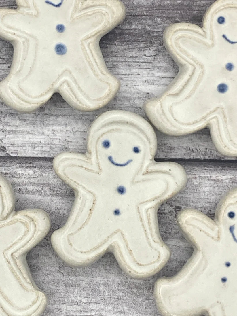 White ceramic gingerbread men with blue details on a wooden surface