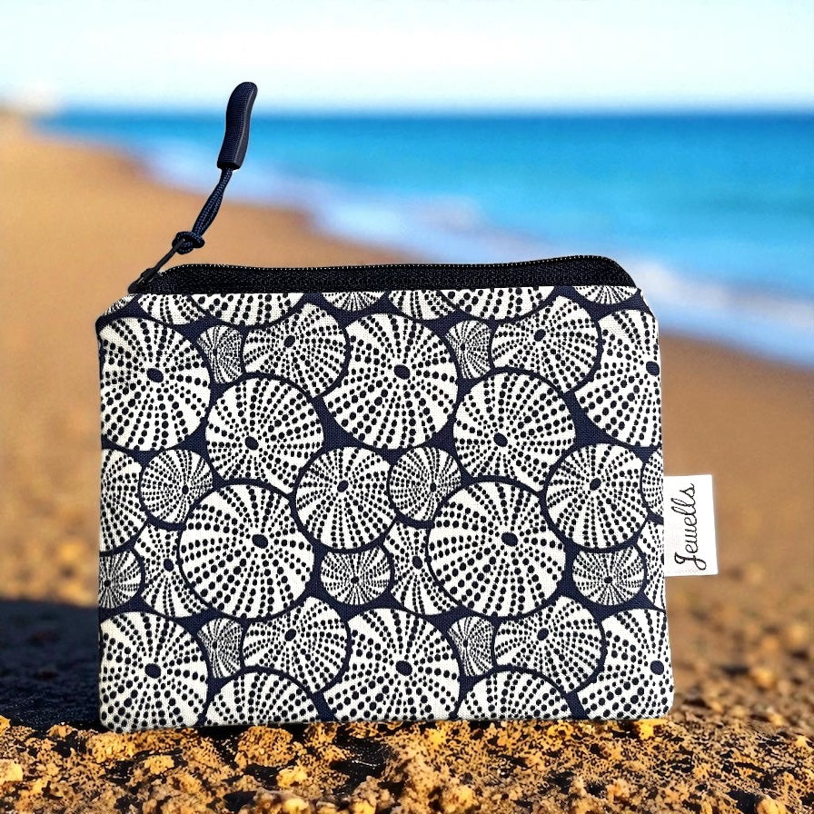 Navy blue and white sea urchin patterned pouch with a beach background