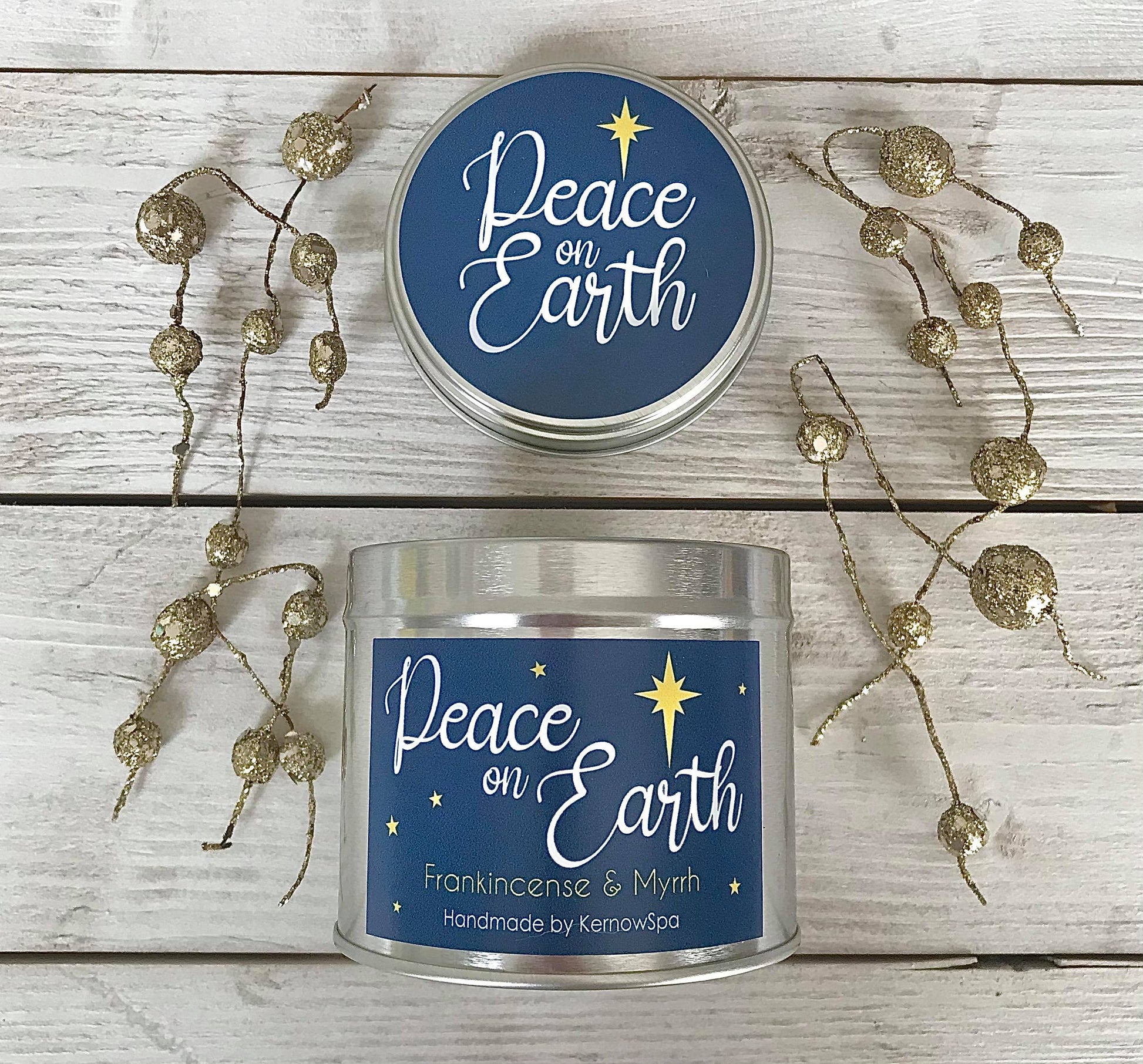 Candle with 'Peace on Earth' label on a wooden surface with decorative elements.