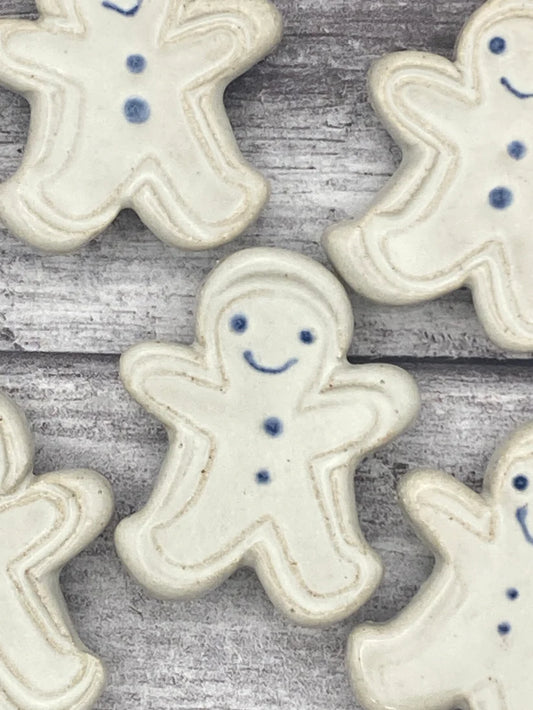 White ceramic gingerbread men with blue details on a wooden surface