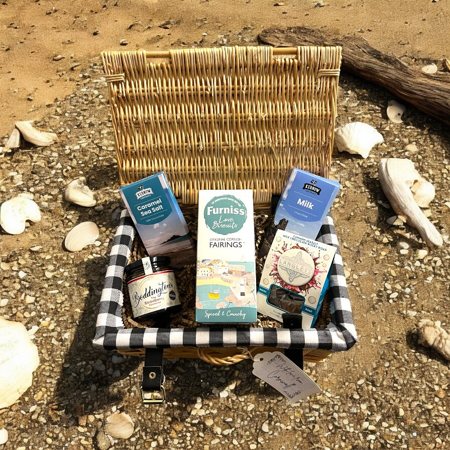 Wicker picnic basket with food items on a sandy surface