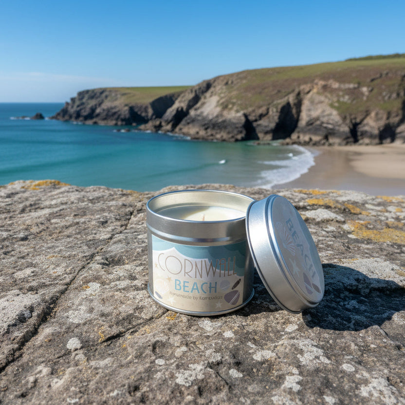 Silver candle tin with Cornwall Beach branding on a cliff top with a beach behind