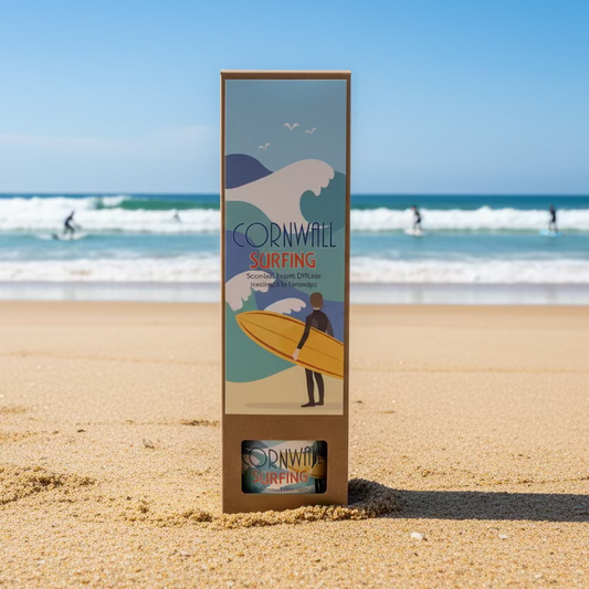 Cornwall surfing reed diffuser sitting on a sandy beach with waves and surfers behind it