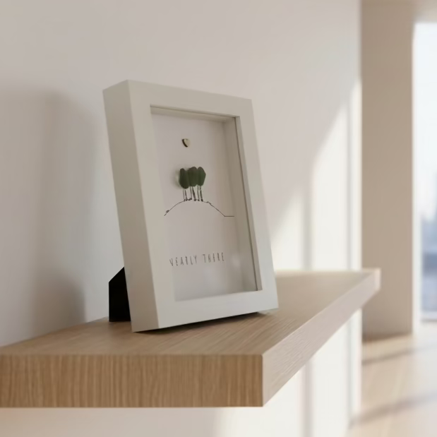 White shadow box with a small tree illustration and text on a wooden surface
