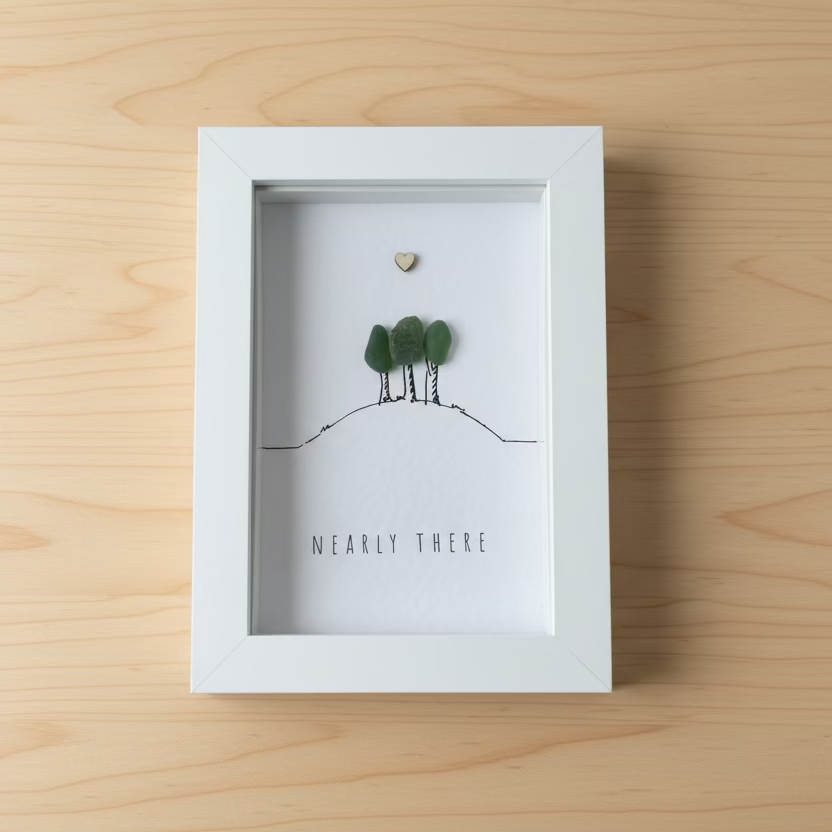 Framed artwork with trees and a heart on a wooden surface