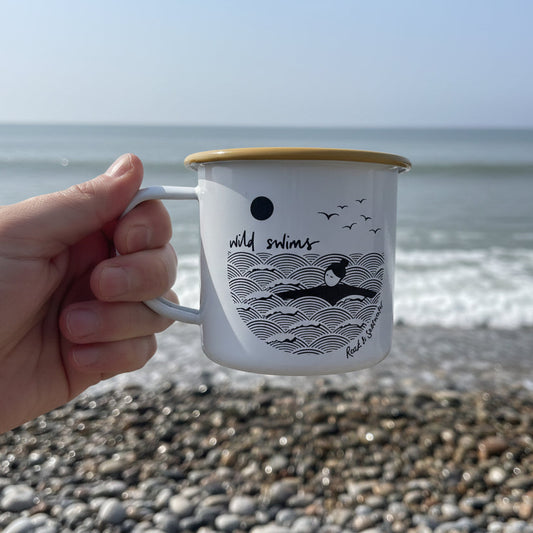 White mug with black graphics and text held in a hand